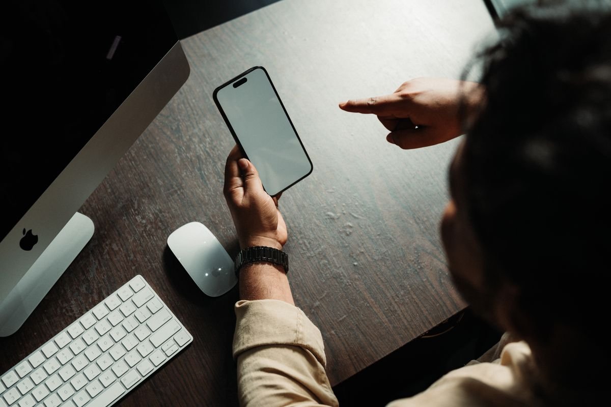 iPhone na mão de uma pessoa sentada à mesa