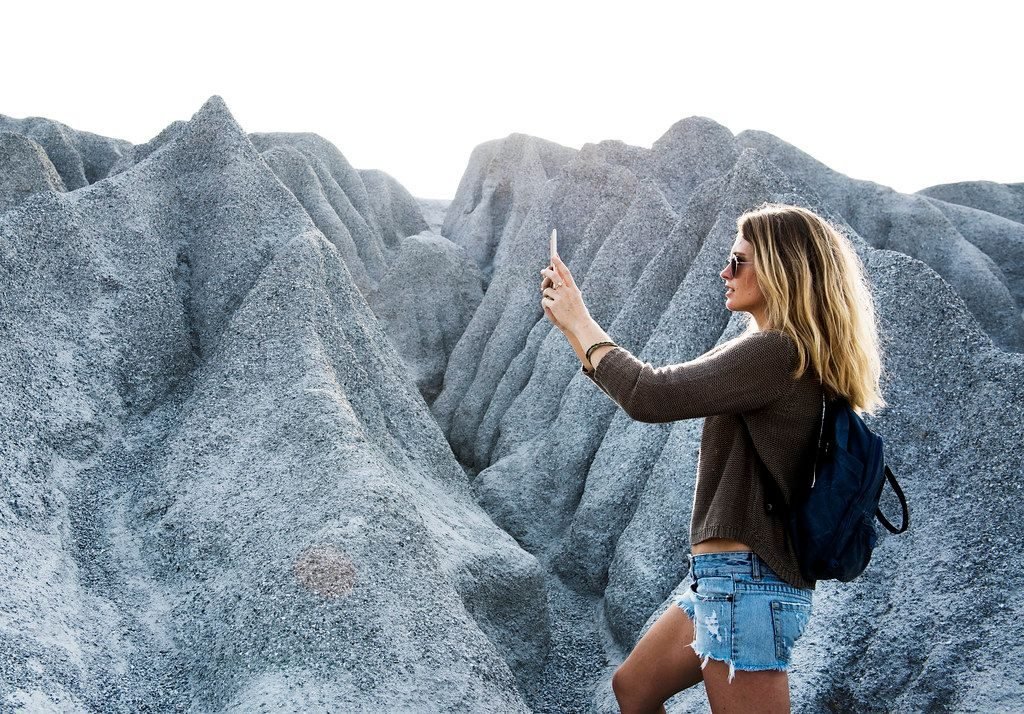 Mulher fotografando com o celular em trilha de pedras