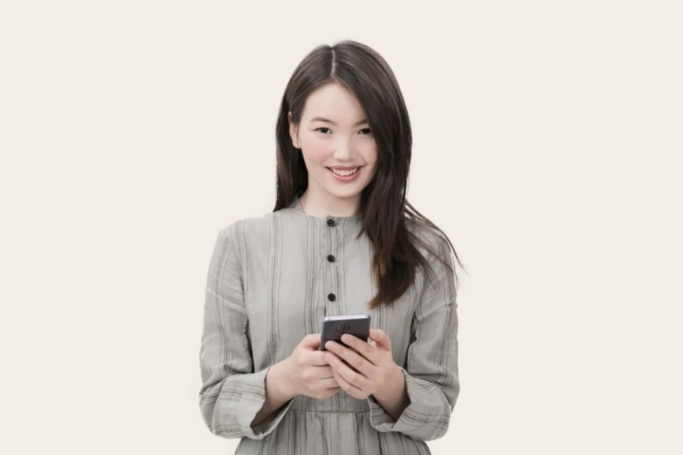 Mulher sorrindo com o celular na mão